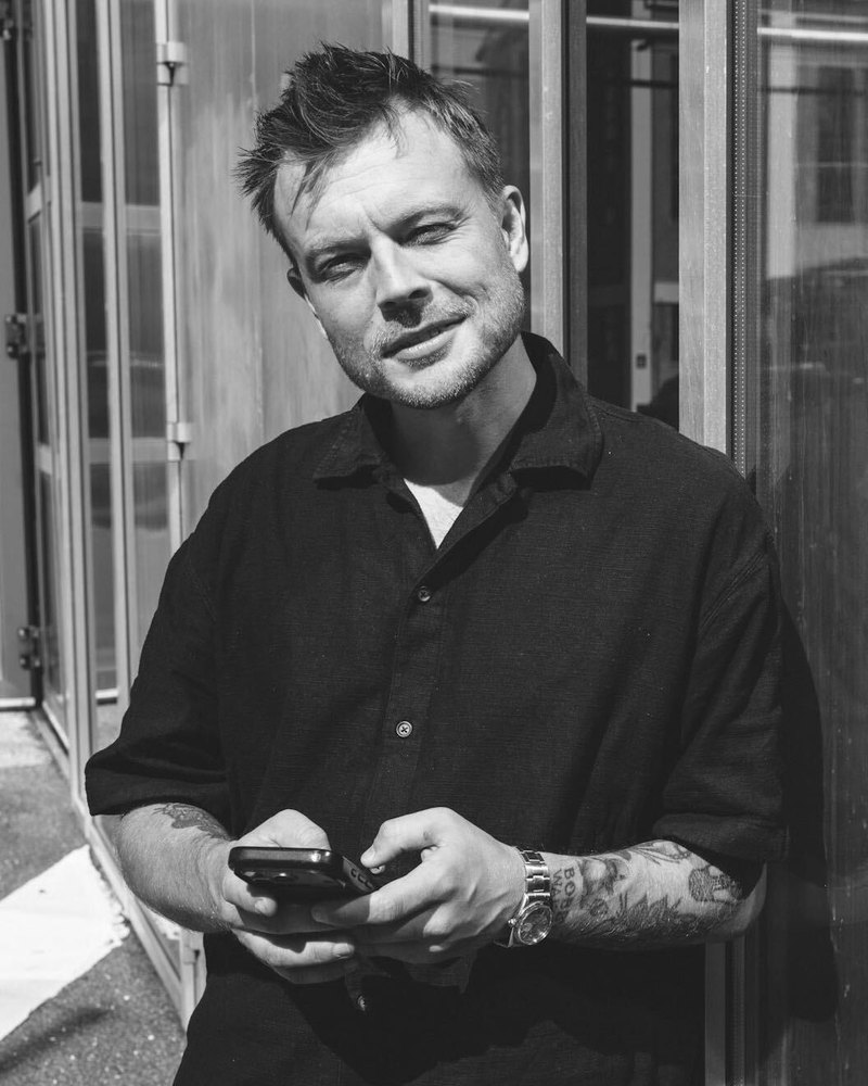 Rasmus lænet op ad en glasfacade i solen