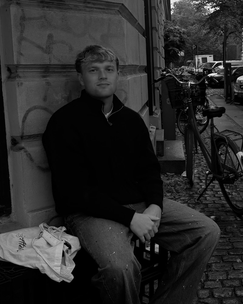 Victor siddende op ad en husmur på en gade